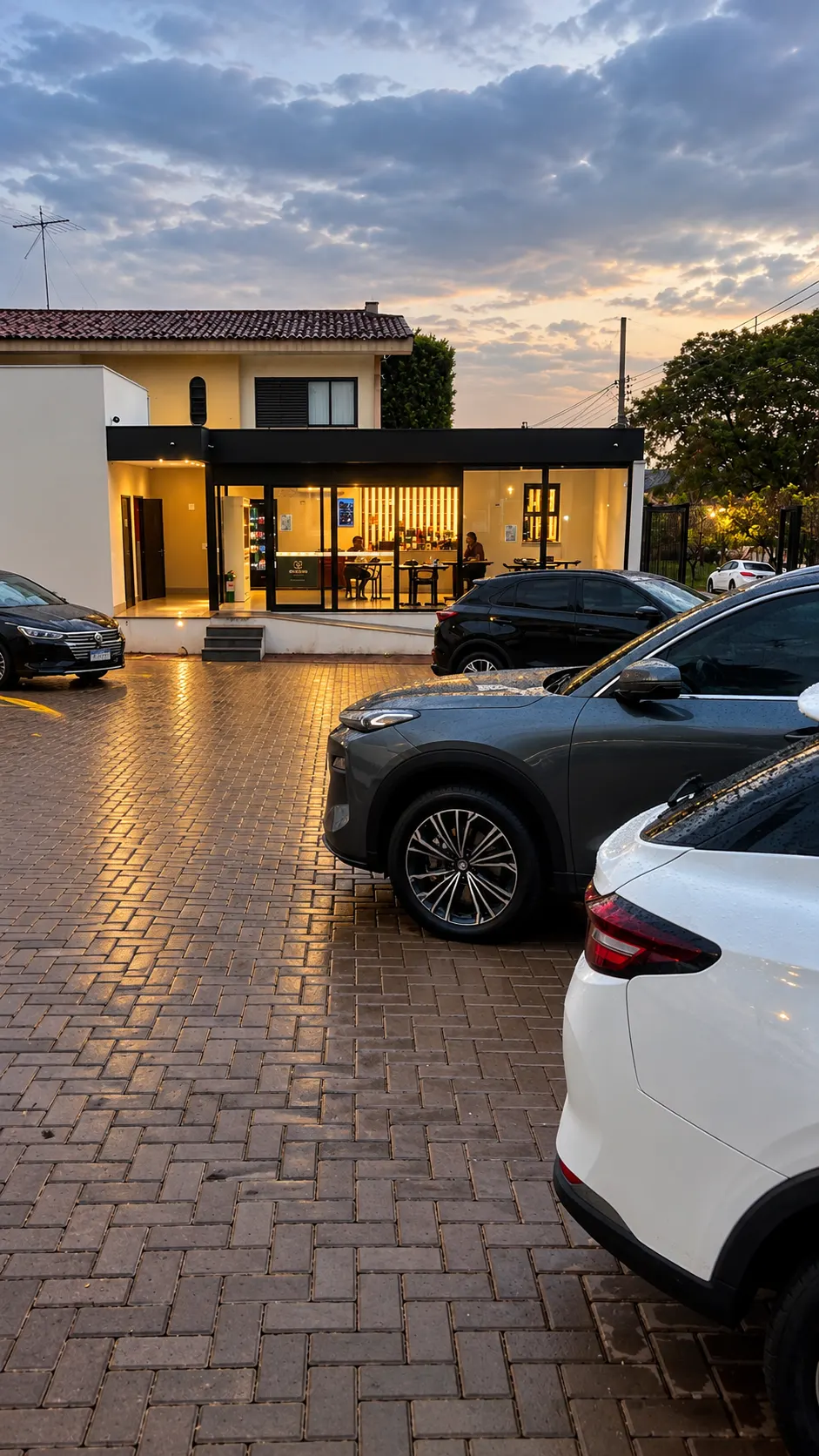 Fachada da conveniência EV Charging ao entardecer com carros elétricos estacionados